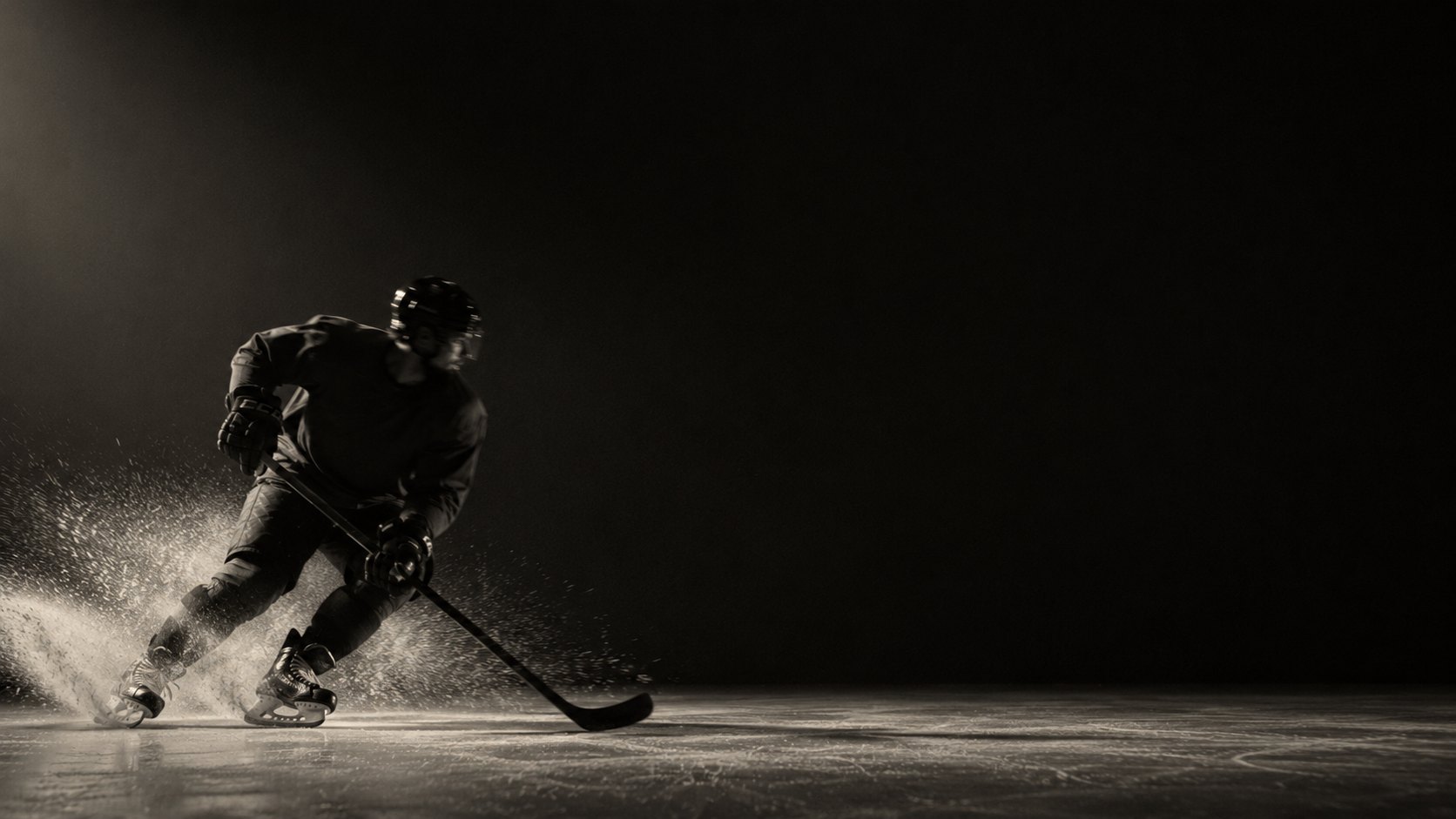 A young hockey player carving hard across the ice, spray rising off the blades